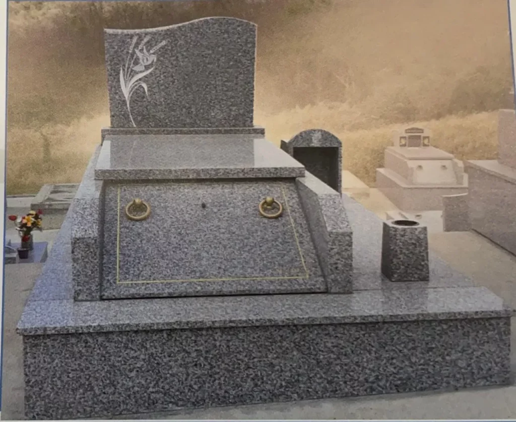 Monument funéraire en granit gris poli avec gravure de fleur blanche.