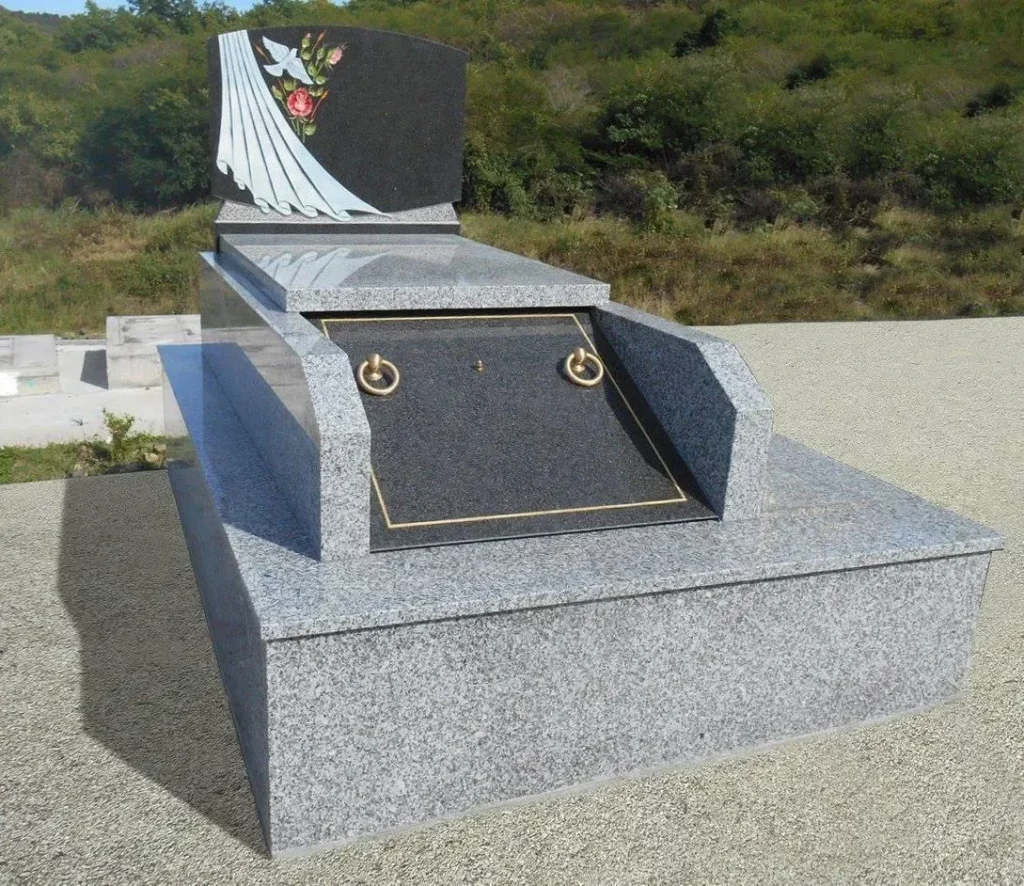 Monument funéraire en granit gris poli avec gravure de colombe et fleurs.
