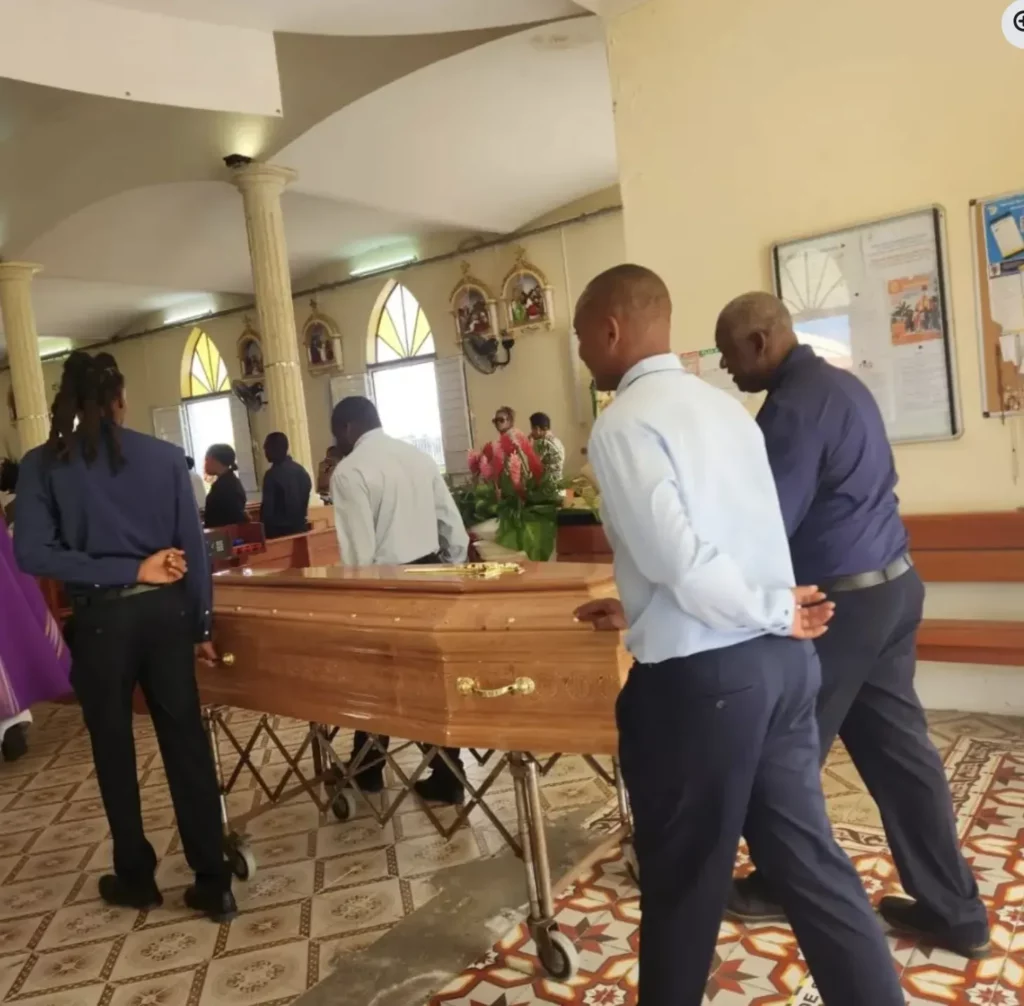 Agents funéraires transportant un cercueil en bois dans une église.